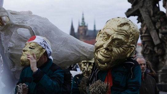 A man in a mask depicting Milos Zeman marches during commemorations for the anniversary of the Velvet Revolution.