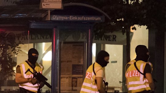 Masked police stand at a bus stop in front of the Olympia mall where a shooting took place in Munich.