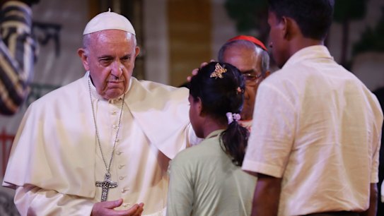 Pope Francis touches the head of a Rohingya Muslims refugee during an interfaith and ecumenical meeting for peace in the garden of the archbishop's residence, in Dhaka, Bangladesh.