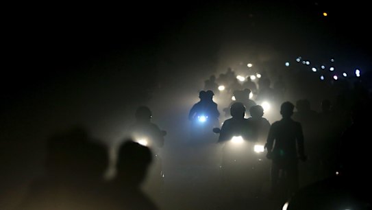 Indian motorists ride past a thick blanket of smog and dust on the outskirts of Delhi, India. 