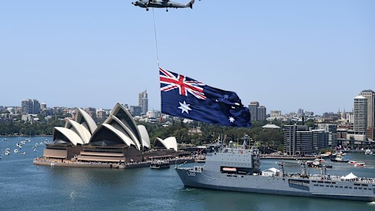A Royal Australian Navy MH-60R Seahawk helicopter flies an Australian flag over Sydney Harbour during Australia Day.