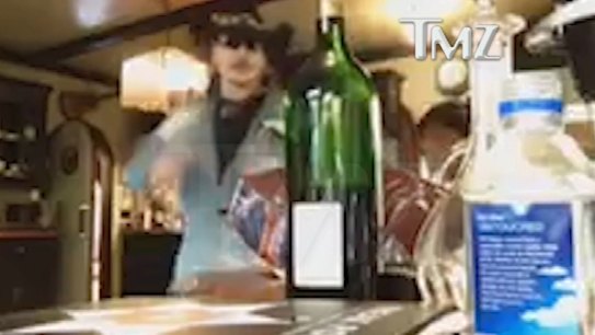 Johnny Depp reaches for a bottle of wine in the video.