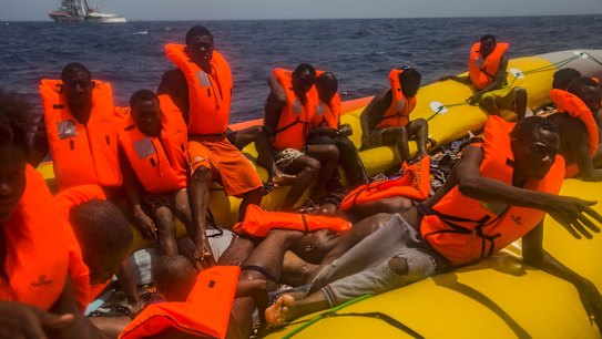Migrants wait to be rescued by aid workers next to the dead bodies of other migrants in the Mediterranean Sea.