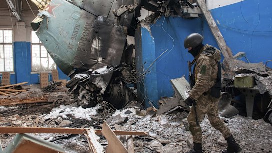 A Ukrainian serviceman walks past the vertical tail fin of a Russian Su-34 bomber lying in a damaged building in Kharkiv, Ukraine, Tuesday, March 8, 2022. (AP Photo/Andrew Marienko)