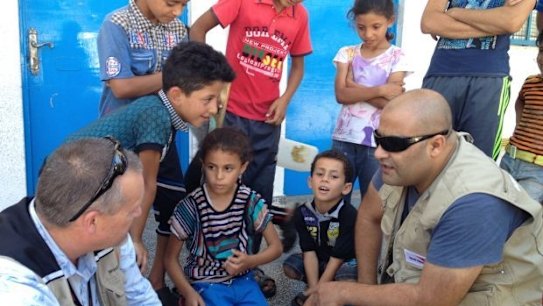 Mohammed Al Halabi, right, is seen talking to children in his work as Gaza program manager for World Vision.