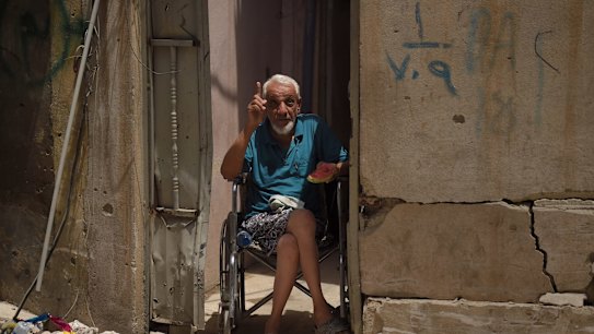 Abdulsalam Abufader, 73, eats watermelon as he sits in his wheelchair at the entrance of his home in West Mosul, Iraq. 