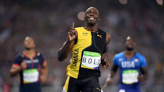 Three-time champion: Usain Bolt celebrates winning the 100m final, with Justin Gatlin, right, finishing second.