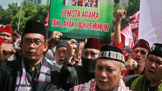 Muslim protesters shout slogans as they hold up a placard with a picture depicting Jakarta governor Basuki "Ahok" Tjahaja Purnama behind bars.
