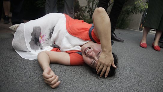 Fan Lili, wife of imprisoned activist Gou Hongguo, on the ground after an interaction with a police officer outside the Tianjin court.