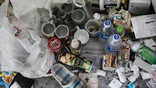 The small apartment was full of instant-noodle bowls, soft-drink bottles and empty cans of coffee.