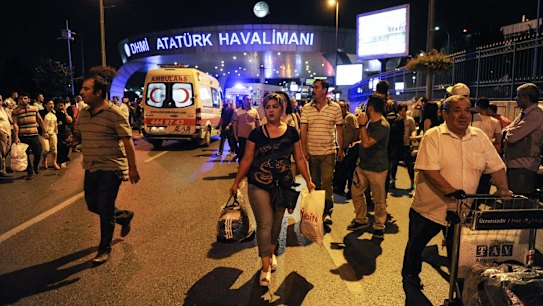 Passengers leave the Turkey's largest airport, Istanbul Ataturk after the suicide bomb attacks as ambulances enter to the site. 