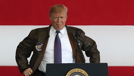 President Donald Trump puts on a military jacket as he meets the US troops at the U.S. Yokota Air Base, on the outskirts of Tokyo on Sunday