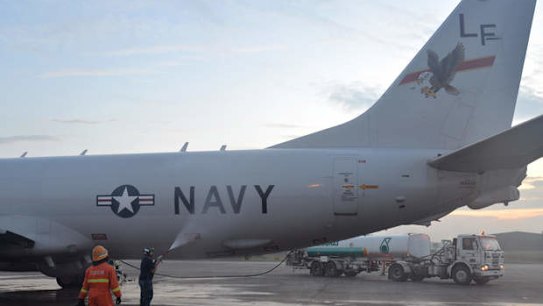 A US Navy airman sprays down a P-8A Poseidon with fresh water before its flight to assist in search and rescue operations for Malaysia Airlines flight MH370.
