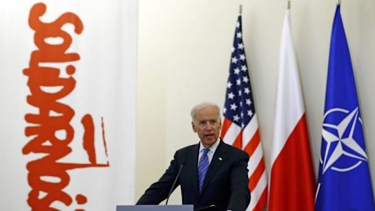 US Vice-President Joe Biden addresses the media in Poland, with US, Polish and NATO flags behind him, as well as a banner from the Solidarity movement which weakened Soviet control over Poland in the 1980s. 