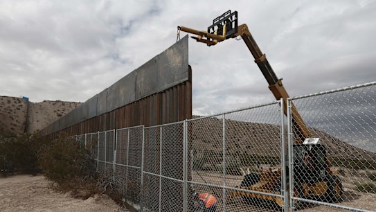 Workers raise a taller fence along the Mexico-US border between the towns of Anapra, Mexico and Sunland Park, New Mexico.