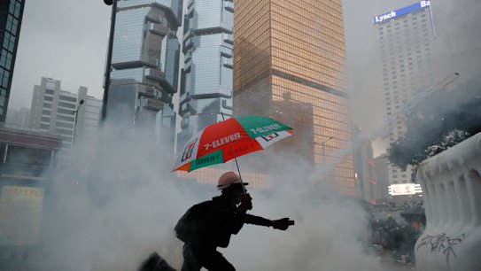 A protester throws back an exploded tear gas shell at police officers.