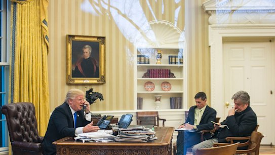Happier times: Trump takes a call with former national security advisor Michael Flynn and Stephen Bannon in attendance, in the Oval Office.