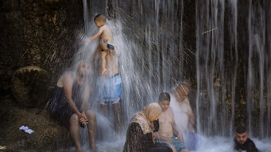 Israeli Arabs stand under a waterfall during the Muslim Eid al-Adha holiday at the Gan HaShlosha national park near the northern Israeli town of Beit Shean.