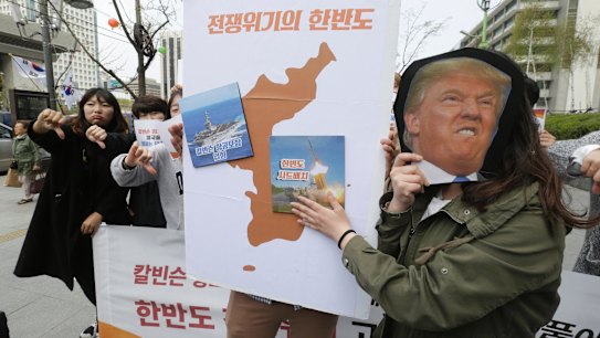 A South Korean protester holds a mask of US President Donald Trump and a Korean Peninsula map during a rally against US deployment in the region outside the US embassy in Seoul.