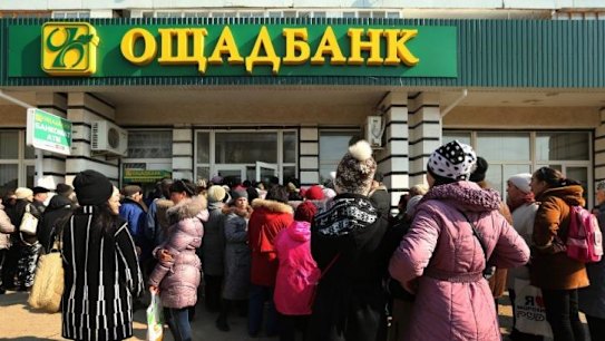 Large crowds gather at the entrance of the Oschadbank in the town of Djankoy.