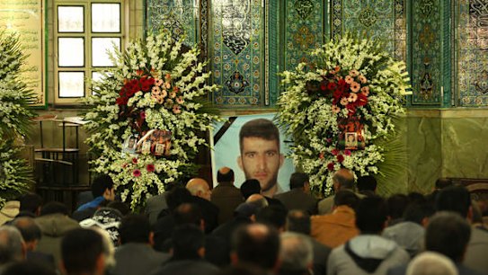 Men gather infront of a large photo of killed asylum seeker Reza Barati during the memorial service in Tehran.