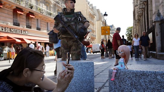 A French soldier stands guard as a tourist takes pictures of her doll in front of Notre Dame cathedral in Paris on Friday.