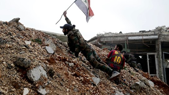 A Syrian army soldier places a Syrian national flag during a battle with rebel fighters  east of Aleppo on December 5.