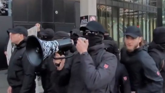 A group of alleged neo-Nazis dressed in black have targeted a refugee rally in Melbourne, unfurling a banner with offensive language.