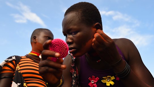 Women from the Mundari Tribe rub red dust into their ears and along their jaw bone as they prepare for the 'Wrestling for Peace' tournament at Juba Stadium where four tribes have come to Juba competing for the prize of cattle and to show that different South Sudanese tribes can live in peace after more than 2 years of war divided the country along ethnic lines.