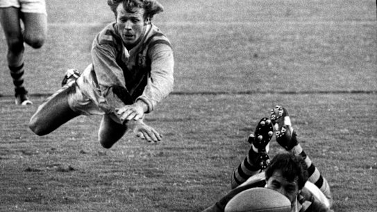 Sydney Firsts centre Bob Fulton looks aggrieved that his airborne attempted tackle is too late to stop Country half-back Brian Burke's disputed try in the Rugby League match at the SCG yesterday. May 19, 1973. 