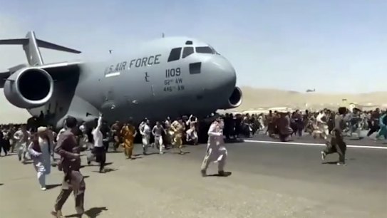 Hundreds of people run alongside a U.S. Air Force C-17 transport plane as it moves down a runway of the international airport, in Kabul, Afghanistan. Thousands of Afghans have rushed onto the tarmac at the airport, some so desperate to escape the Taliban capture of their country that they held onto the American military jet as it took off. 