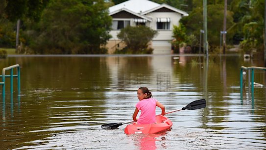 Maleah Jones, 8 years old, canoes up flooded Bright street to her home in Lismore.