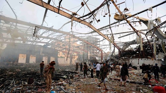 People inspect the aftermath of an air strike in the Yemeni capital, Sanaa, which killed at least 100 people and injured hundreds more.