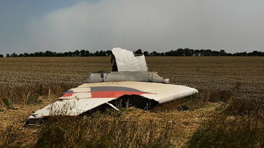 A portion of the MH17 wing lies in the field as smoke rises behind the tree-line. Russians no longer know what to think.