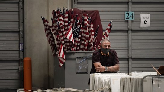 An election warehouse worker takes a break as American flags used on Election Day are stored behind him at the Clark County Election Department in North Las Vegas.