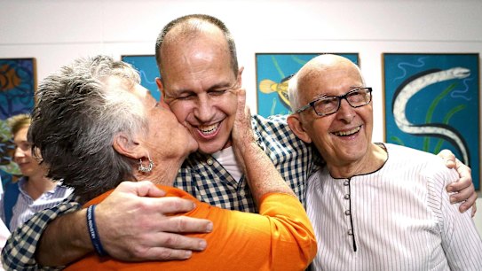 Australian journalist Peter Greste (C) receives a kiss from his mother Lois (L) as he hugs his father Juris upon his return home at Brisbane International Airport, early February 5, 2015. Peter Greste, the Al Jazeera journalist freed after more than a year in an Egyptian prison, arrived back in his Australian homeland on Thursday and called for the release of two colleagues still in custody. Greste was released on Sunday after 400 days in a Cairo jail and had been in Cyprus since. He had been sentenced to seven years on charges that included aiding a terrorist group in a case that had attracted widespread attention and criticism of Egypt's leadership and judiciary.    REUTERS/Nathan Richter   (AUSTRALIA - Tags: MEDIA)