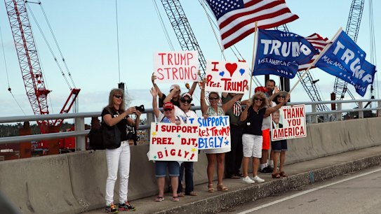Supporters of US President Donald Trump stand on the bridge to his Mar-a-Lago estate in Florida, as his motorcade passes on Saturday.