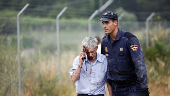An injured man, identified by Spanish newspapers as the train driver Francisco Jose Garzon, is helped by a policeman after a train crashed near Santiago de Compostela, northwestern Spain on July 24.