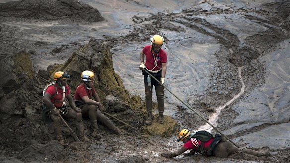 Rescue workers take a rest from their search for victims at the town of Bento Rodrigues, after a dam burst on November 5 in Minas Gerais state, Brazil.
