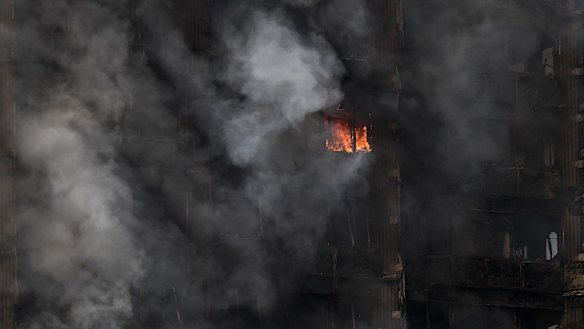 A fire still burns and smoke rises from the building after dawn on Wednesday.