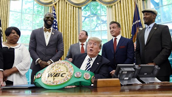 US President Donald Trump speaks after signing an executive order granting a posthumous pardon for Jack Johnson, the first black heavyweight boxing champion, as boxing champion Lenox Lewis, from left, and actor Sylvester Stallone attend in the Oval Office.