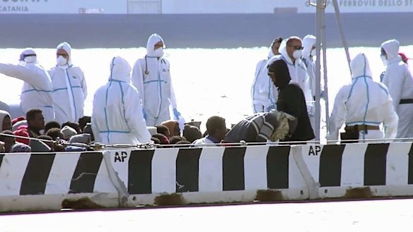 Sitting asylum-seekers, surrounded by emergency relief workers at the Italian port of Messina on Saturday. 