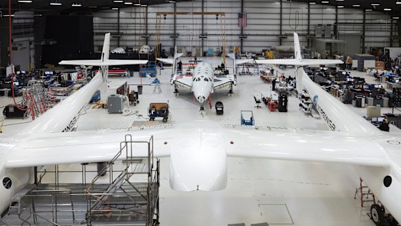 In the Virgin Galactic hangar at the Mojave Air &amp; Space Port, VSS Unity sits between the twin hulls of VMS Eve.