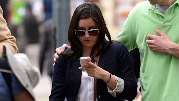 A woman uses her smartphone as crossing street in Washington.