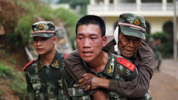 A paramilitary policeman carries an elderly man after the earthquake.
