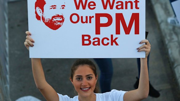 A Lebanese woman holds a placard supporting the outgoing Lebanese Prime Minister Saad Hariri to return from Saudi Arabia during the Beirut Marathon, in Beirut, Lebanon, on Sunday.