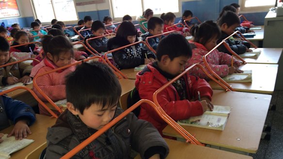 Chinese children read books with special desks equipped with iron bars to help them protect their eyesight.