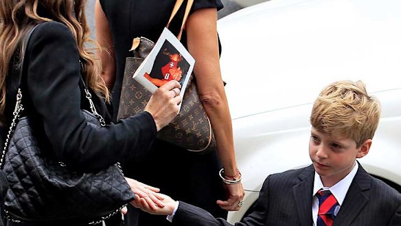 Jim's son Tiernan holds on to mum Sam's hand as the family prepares to leave the funeral service.