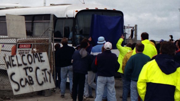 Picketers stand in front of a bus trying to pass through. A sign reads "Welcome to Scab City" at Webb Dock, Melbourne. April 8, 1998.