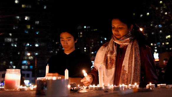 People light candles at a makeshift memorial to victims after a van mounted a footpath, crashing into pedestrians in Toronto in April.
